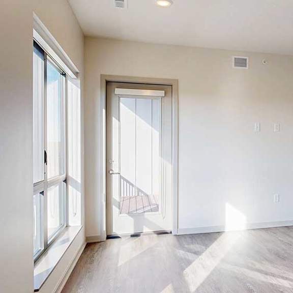 Thumbnail 11 of 30 a spacious living room with a windowed door to a balcony and a door to a bedroom