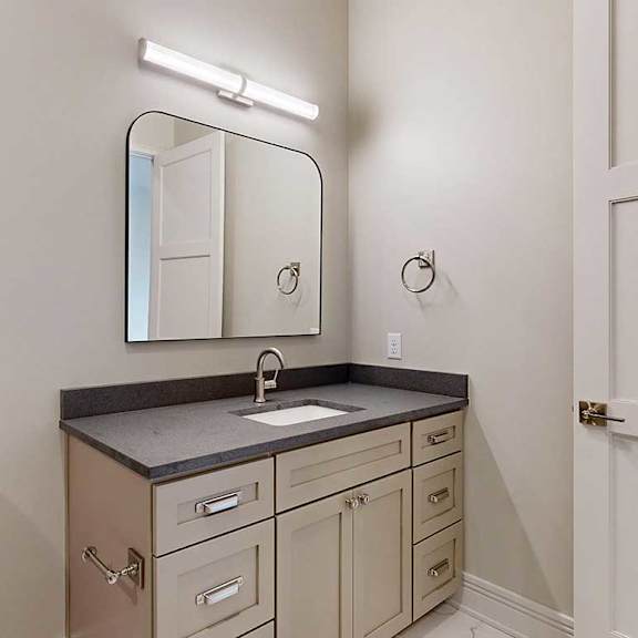 Thumbnail 25 of 41 A bathroom with a wide quartz vanity sink, a framed mirror, and overhead lighting.