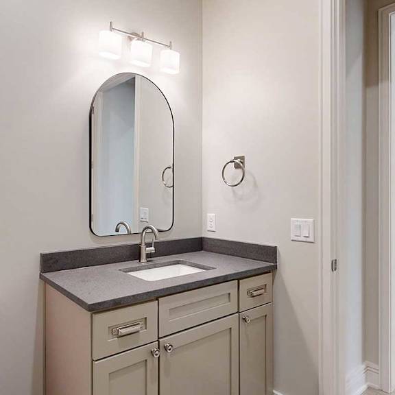 Thumbnail 28 of 41 A half bathroom with a quartz vanity sink and a mirror with overhead lighting.