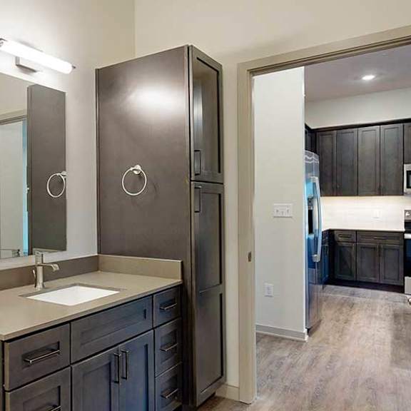 Thumbnail 23 of 26 a bathroom with a sink, mirror, and a tall storage cabinet