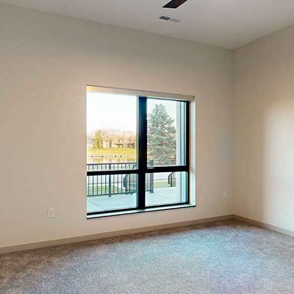 Thumbnail 17 of 26 a bedroom with carpeted flooring and a large window looking out to the walk-out patio