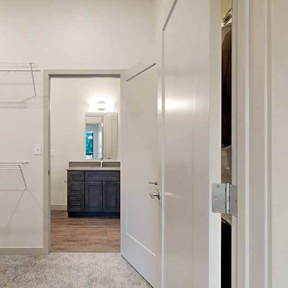 Thumbnail 22 of 26 a walk-through closet with built-in shelving and a door to a bathroom