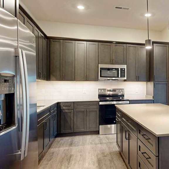 Thumbnail 3 of 26 a modern kitchen with dark wood cabinets, stainless steel appliances, and quartz countertops
