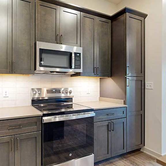 Thumbnail 4 of 26 a kitchen with dark cabinets, white quartz countertops, and stainless steel microwave and oven
