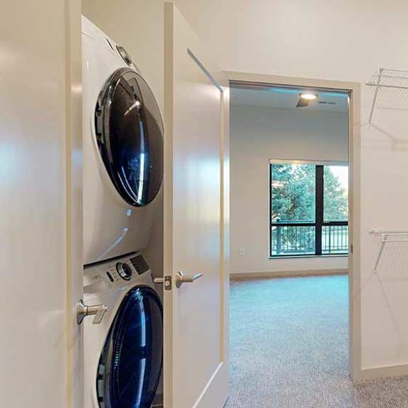 Thumbnail 20 of 26 a walk-through closet with a washer and dryer and a doorway leading to the bedroom