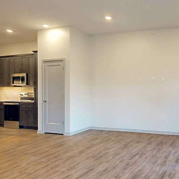Thumbnail 9 of 26 a spacious living room with wooden flooring and a kitchen to the left