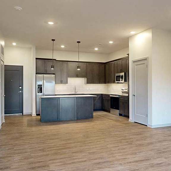 Thumbnail 15 of 26 an open living room next to a kitchen with dark cabinets and a large central island