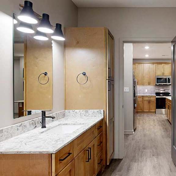 Thumbnail 26 of 26 A bathroom with a white granite countertop and wooden cabinets