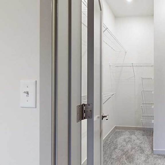 Thumbnail 20 of 25 an L-shaped walk-in closet with build-in shelving and hanging space