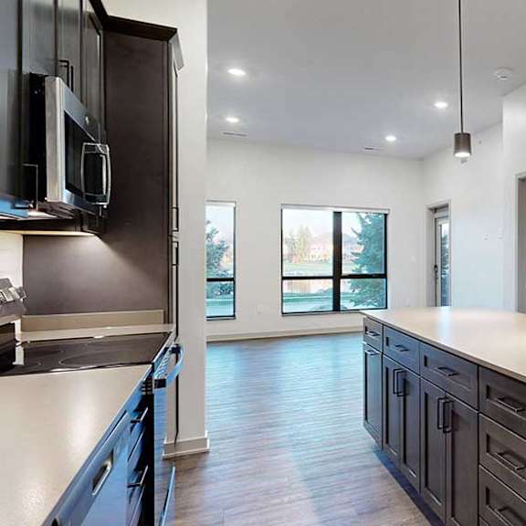Thumbnail 6 of 25 a modern kitchen with dark cabinets and a large island