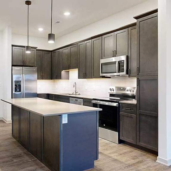 Thumbnail 8 of 25 a modern kitchen with dark wood cabinets and a central island next to a front door