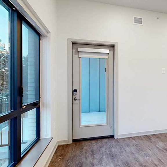 Thumbnail 11 of 25 a living room with wooden flooring and a windowed door to a patio