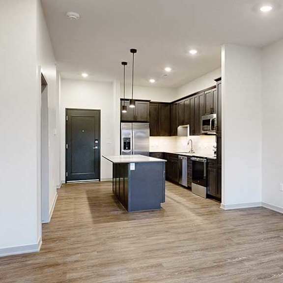 Thumbnail 15 of 25 an open living room next to a kitchen with dark cabinets