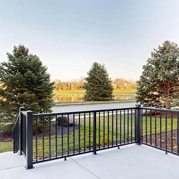 Thumbnail 13 of 25 a black metal railing of a patio in front of trees and a pond