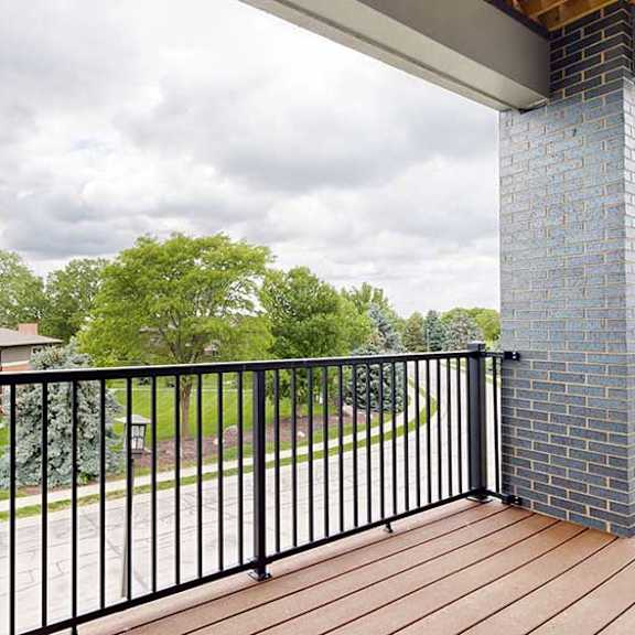 Thumbnail 23 of 33 A balcony with a black metal railing, a brick pillar and a view of the neighborhood.