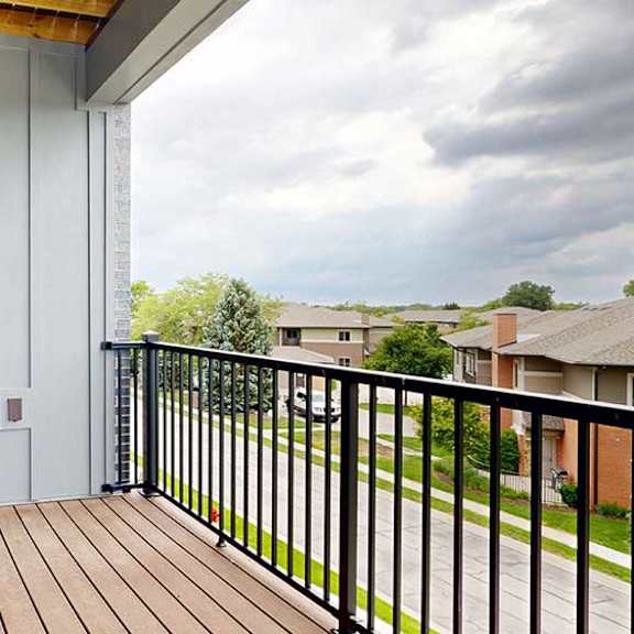 Thumbnail 25 of 33 A balcony with a black metal railing, a windowed door to the living room, and a view of the neighborhood.