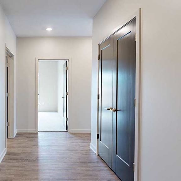 Thumbnail 4 of 33 A hallway with a closet to the side, and an open door to a bedroom at the end.