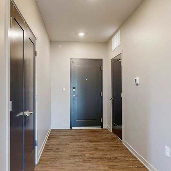 Thumbnail 2 of 33 A hallway with a closet to the side, with a front door at the end.