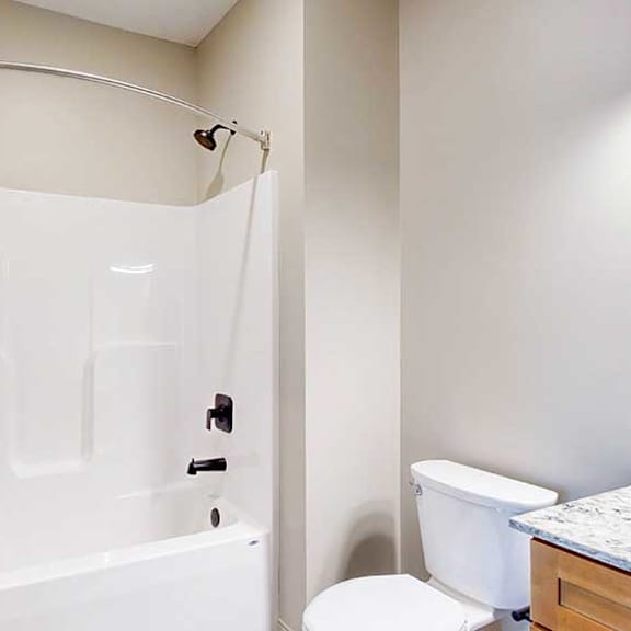 Thumbnail 10 of 33 A bathroom with a white tub shower with black finishes, and a curved shower curtain rod.