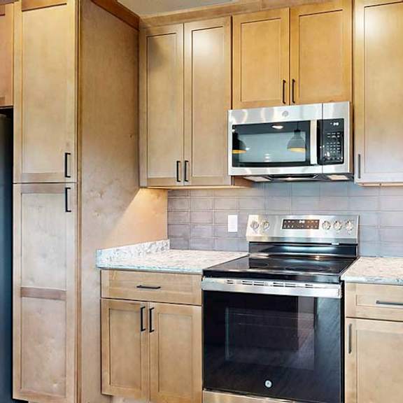 Thumbnail 19 of 33 A close up of the stainless steel microwave and range in a kitchen with warm wooden cabinets.