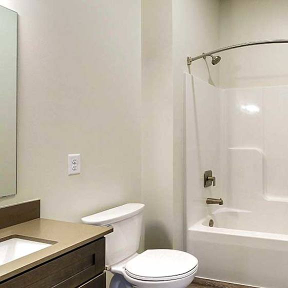 Thumbnail 7 of 33 a bathroom with a white shower tub, and the edge of a vanity sink with quartz countertop
