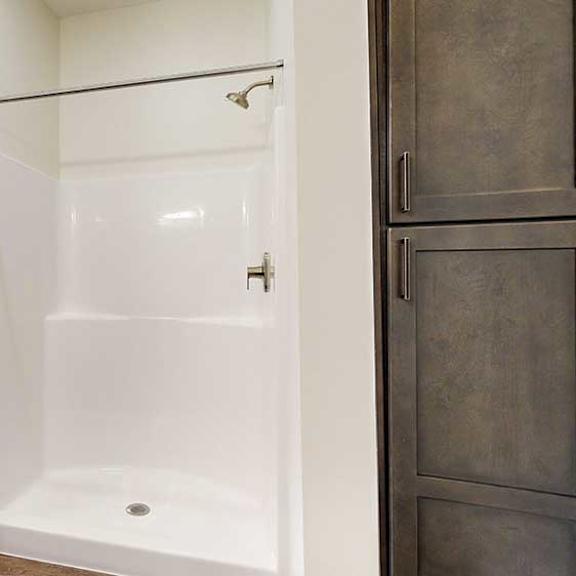 Thumbnail 32 of 33 a bathroom with a walk-in shower next to a tall dark wooden storage cabinet
