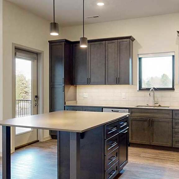 Thumbnail 16 of 33 a kitchen with dark wood cabinets, a large kitchen island table, stainless steel appliances, and light quarts countertops