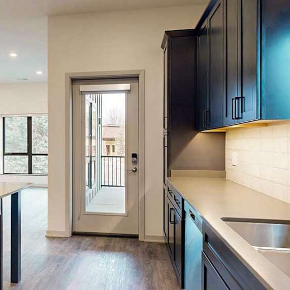 Thumbnail 17 of 33 a kitchen with dark cabinets, quartz counter tops, tile backsplash, and a door to the walk-out patio