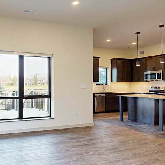 Thumbnail 12 of 33 a spacious living room with hardwood floors and a window looking out onto the walk-out patio