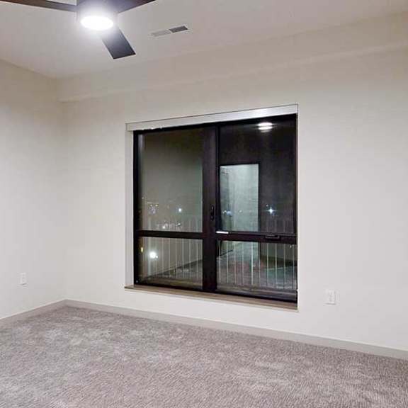 Thumbnail 17 of 25 a bedroom with a large window, carpeted flooring, and a ceiling fan