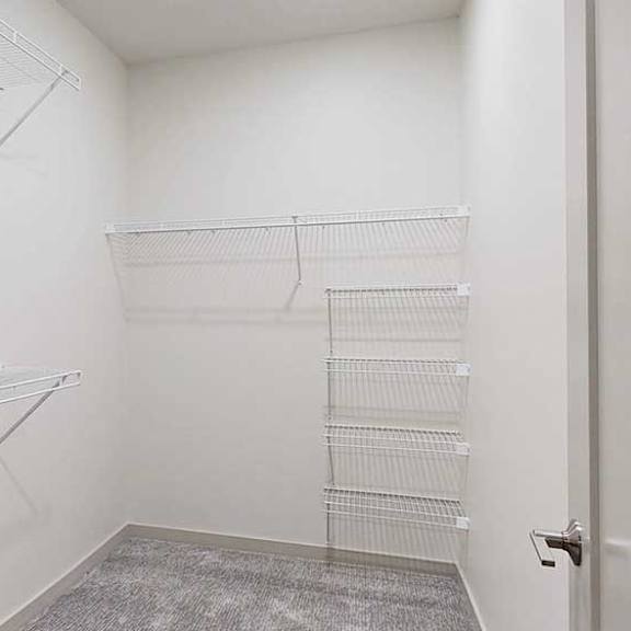 Thumbnail 20 of 25 a white walk in closet with built in shelves and hanging space