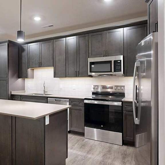 Thumbnail 5 of 25 a modern kitchen with dark wood cabinets and stainless steel appliances