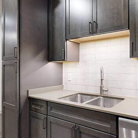 Thumbnail 7 of 25 a kitchen with black wood cabinets, light tile backsplash, and a stainless steel sink