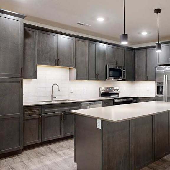 Thumbnail 9 of 25 a modern kitchen with dark wood cabinets, quartz countertops, and stainless steel appliances
