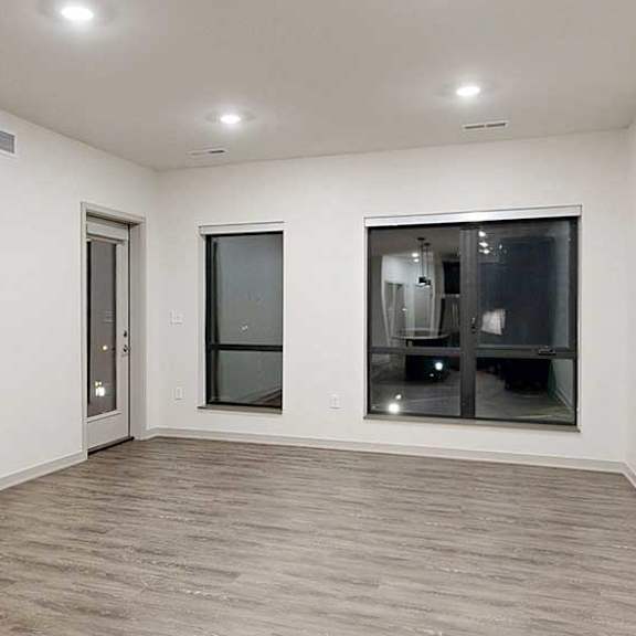 Thumbnail 10 of 25 a living room with two large windows, a windowed door to the balcony, and hardwood flooring