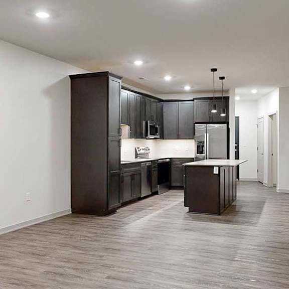 Thumbnail 15 of 25 an open living room and modern kitchen featuring dark wood cabinets and a large central island