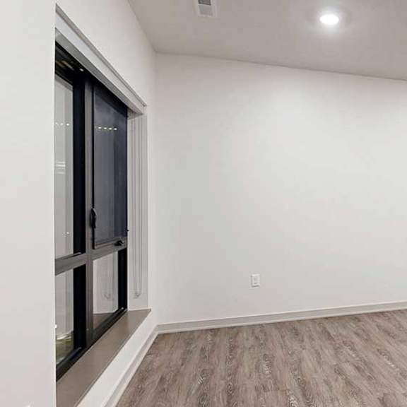 Thumbnail 11 of 25 a living room with a wide wall and a large window next to a kitchen with dark wooden cabinets
