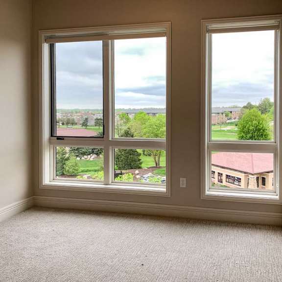 Thumbnail 11 of 26 a bedroom with floor-to-ceiling windows overlooking a residential area