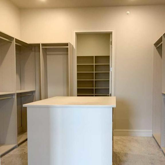 Thumbnail 23 of 26 a spacious walk-in closet with built-in shelving and hanging space, and a central storage island