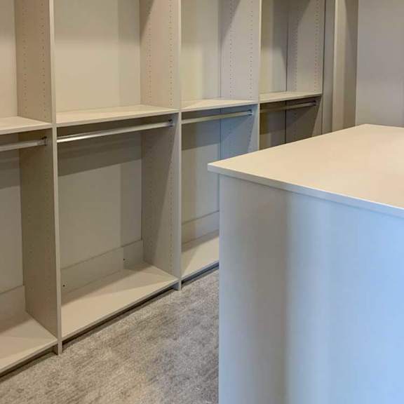 Thumbnail 24 of 26 a spacious walk-in closet with built-in hanging spaces and a central cabinet