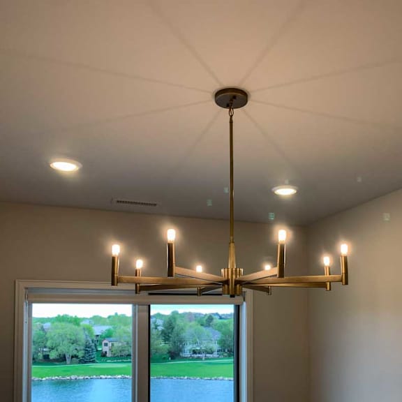 Thumbnail 8 of 26 a chandelier with eight candle-style lights hangs from the ceiling in a room with a view of a pond and trees outside the window
