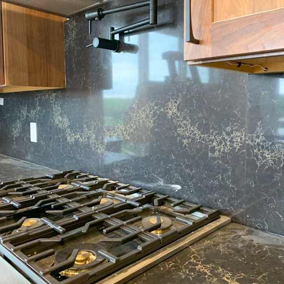 Thumbnail 7 of 26 a modern kitchen with a gas stove top with six burners, a black marble backsplash, and a pot-filler faucet
