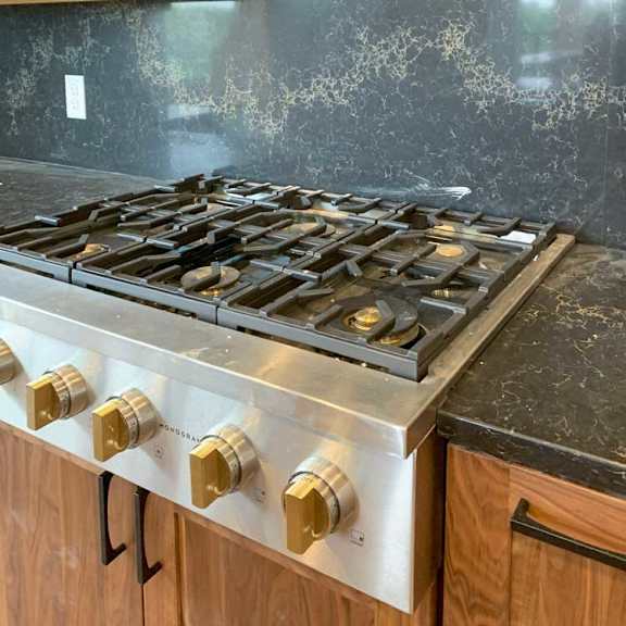 Thumbnail 6 of 26 a stainless steel gas stove with six burners, a pot-filler faucet, and a marble backsplash