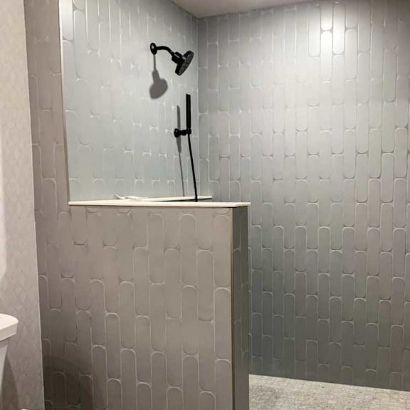 Thumbnail 17 of 26 a bathroom with a large tiled walk-in shower with a built-in divider wall