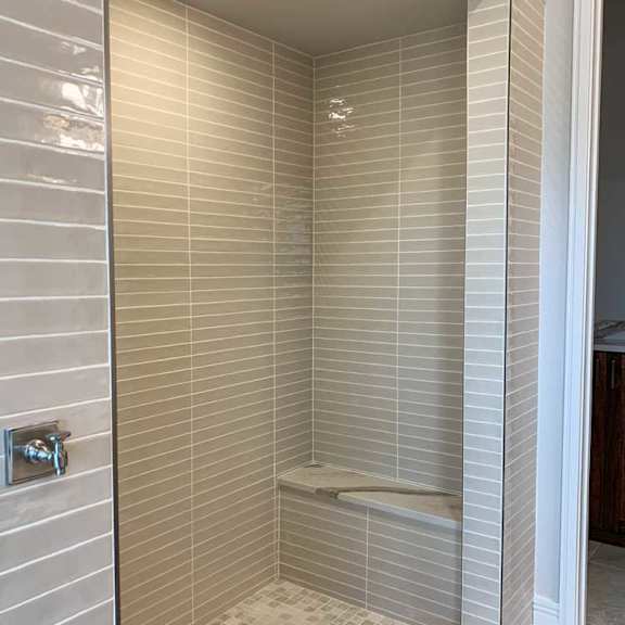 Thumbnail 22 of 26 a tiled walk-in shower with a built-in bench for seating