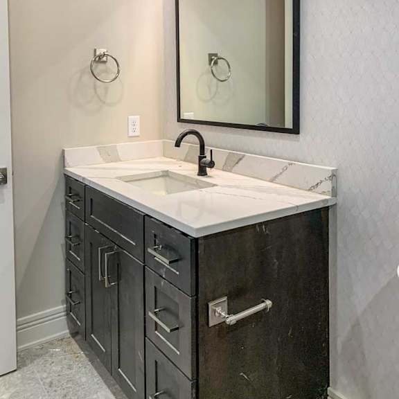 Thumbnail 15 of 26 a hallway bathroom with a dark wooden sink and white marble countertop with a wide mirror