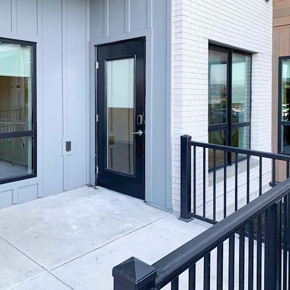 Thumbnail 14 of 29 a walk-out patio with a black railing and large windows from the bedroom and living room