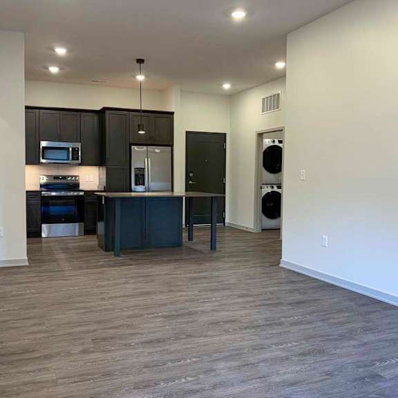 Thumbnail 16 of 29 a view of the kitchen with dark cabinets and a large island from the living room