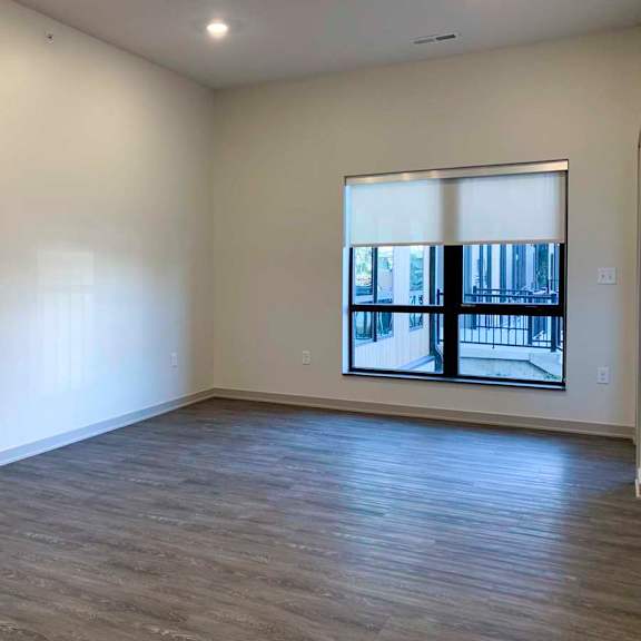 Thumbnail 10 of 29 a living room with a large window and wooden flooring