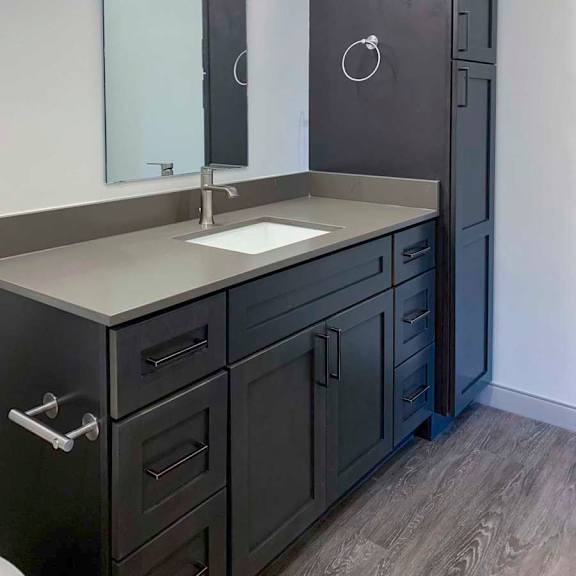Thumbnail 22 of 29 a bathroom with a quartz vanity sink, mirror, and dark wooden cabinetry